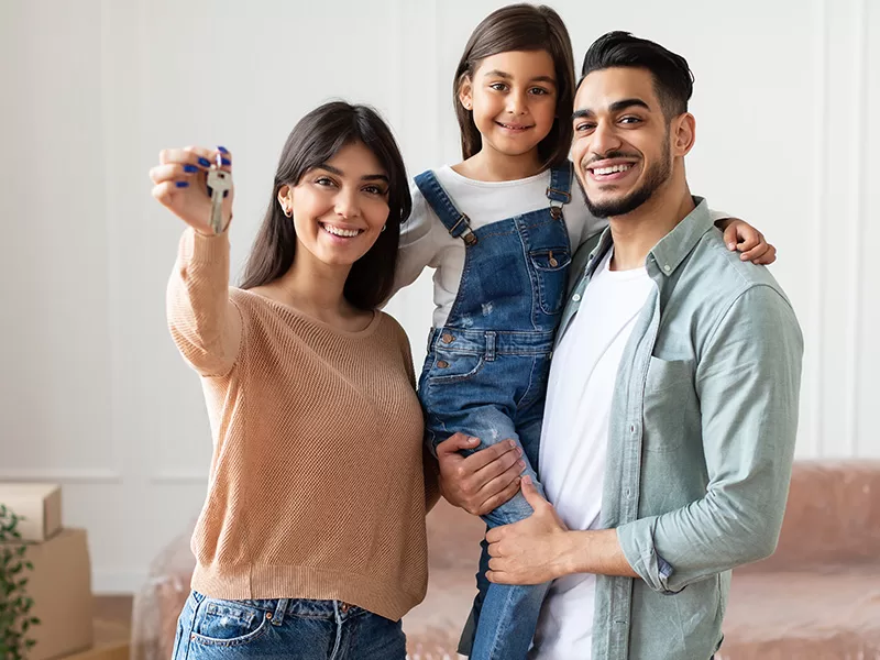 Happy family with house keys celebrating their new home, made possible by Arbor Financial Group's $15,000 Closing Cost Grant.